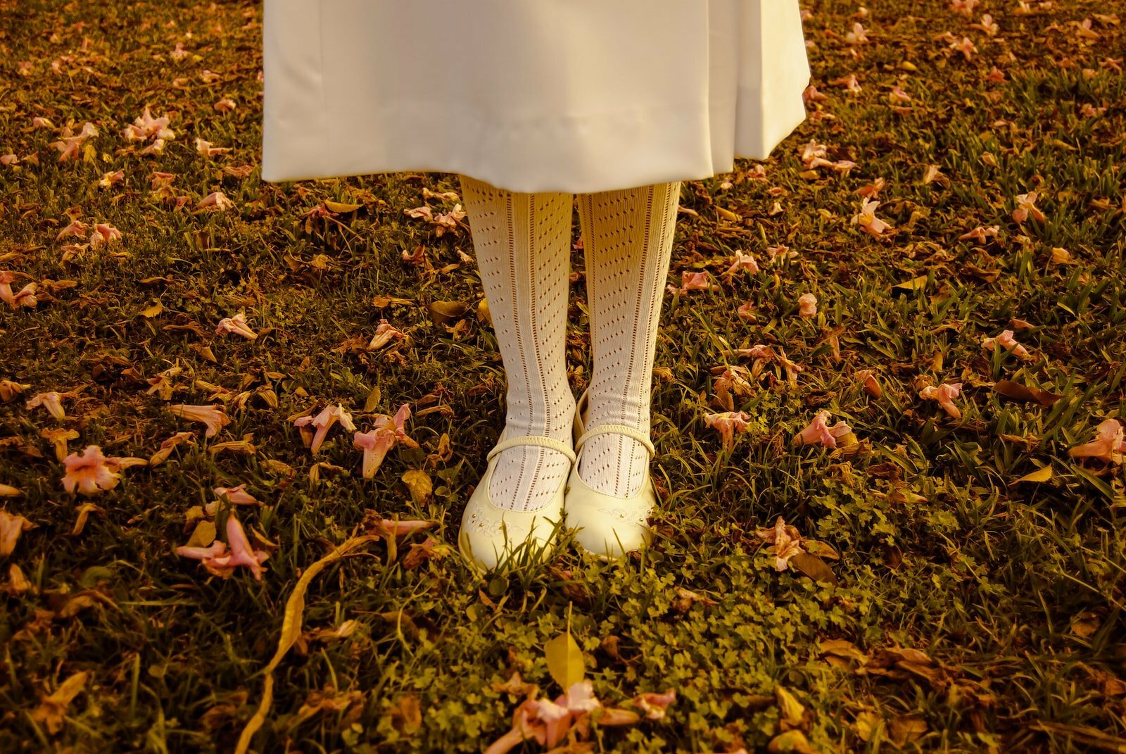 girl standing on grass wearing white dress and shoes during daytime