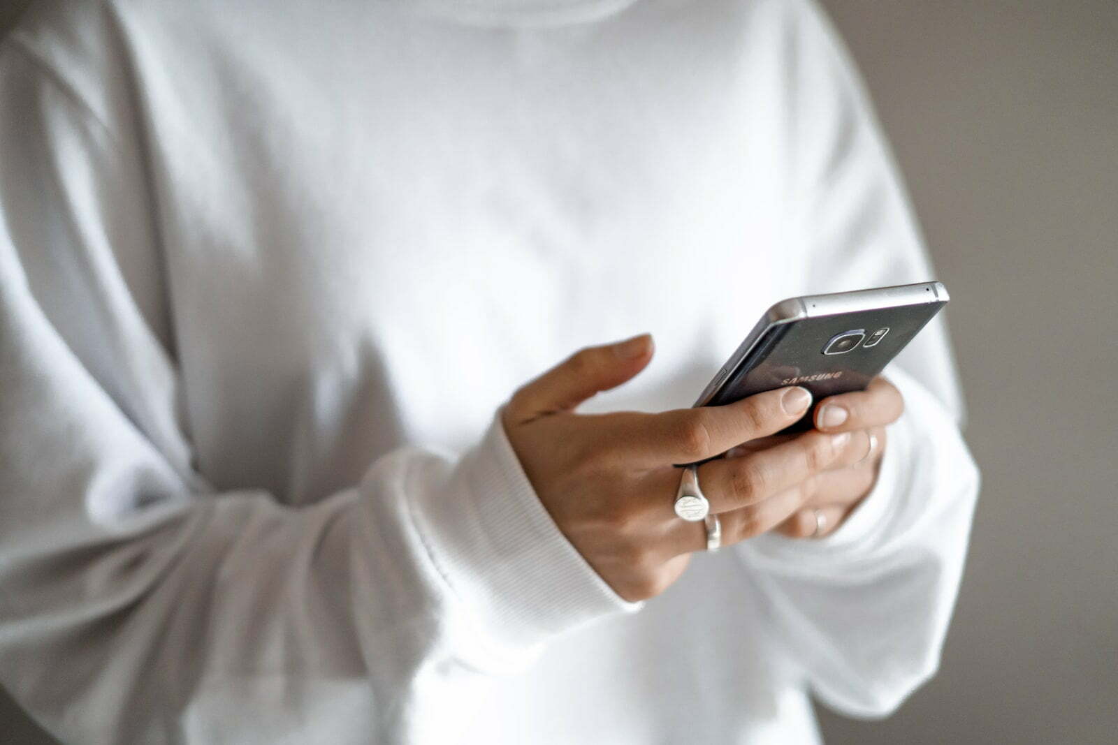 person in white long sleeve shirt holding black smartphone