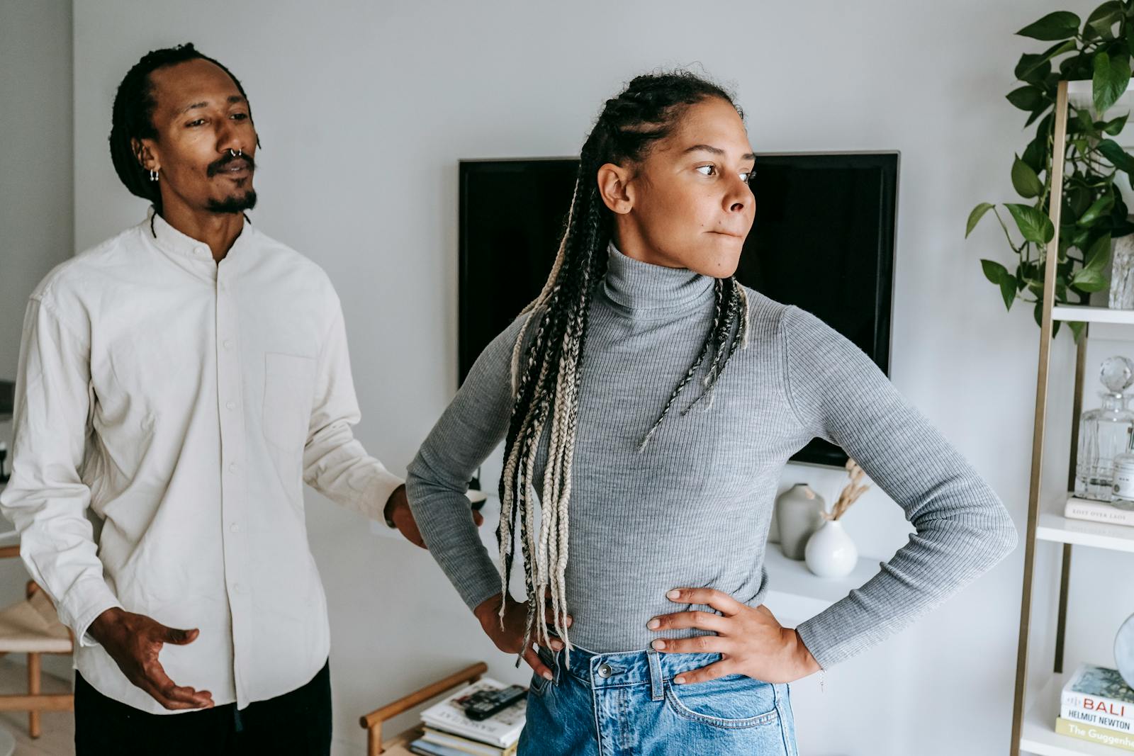 Unhappy African American couple quarreling while spending time together in light modern apartment